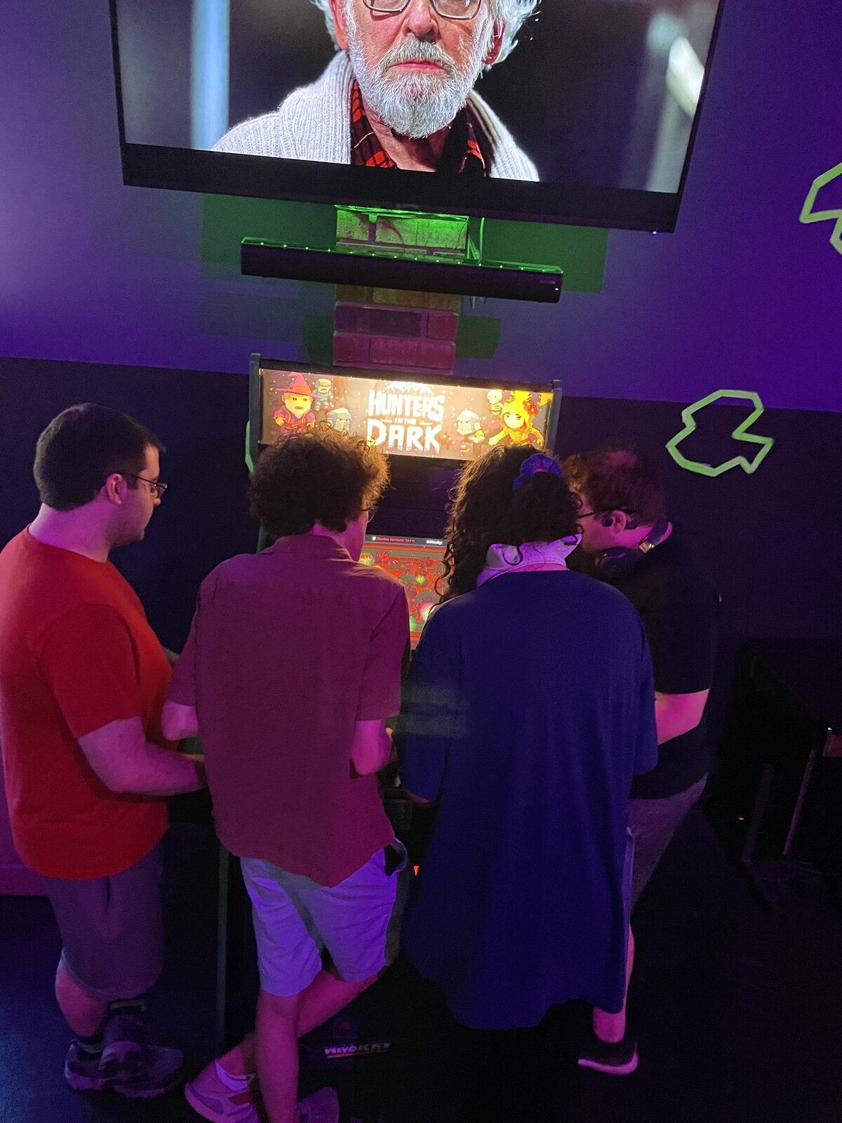 A group gathered around the Hunters In The Dark arcade cabinet